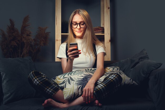 Jeune femme à l'aide de téléphone portable. Assis sur le canapé.