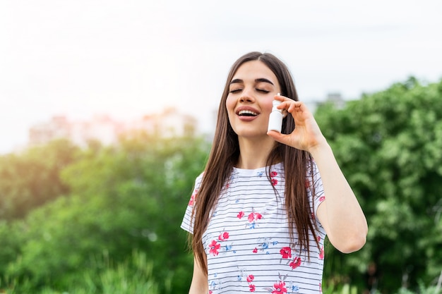 Jeune femme à l'aide d'un vaporisateur nasal pour ses allergies au pollen et à l'herbe