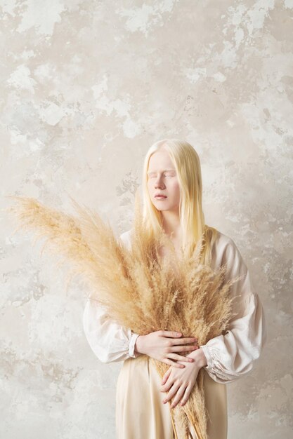 Jeune femme albinos avec bouquet de fleurs séchées moelleuses dans les mains