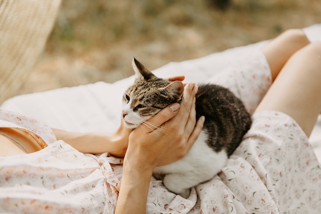 Jeune femme allongée sur un lit, à l'extérieur, dans la cour et jouer avec un chaton