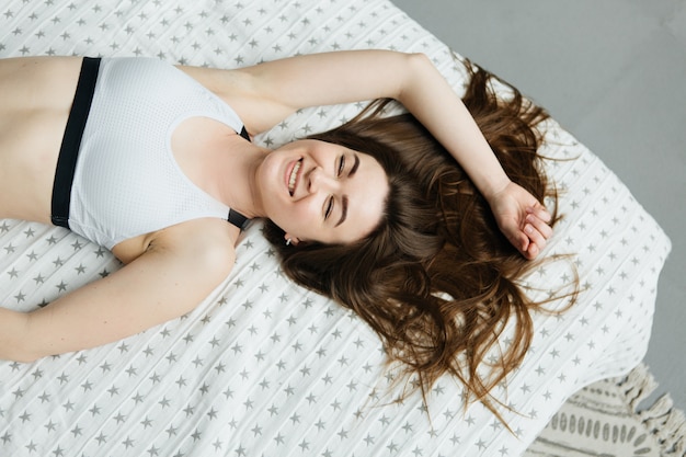 Jeune femme allongée sur le lit. Fille dans une chambre lumineuse.