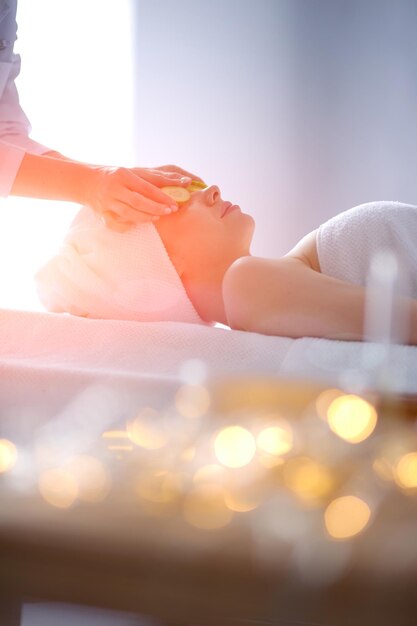 Jeune femme allongée sur une table de massage relaxante avec les yeux fermés femme spa salon