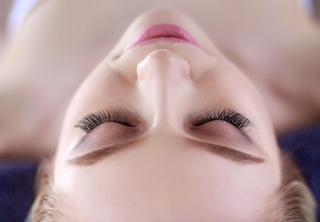 Jeune femme allongée sur une table de massage relaxante avec les yeux fermés femme spa salon