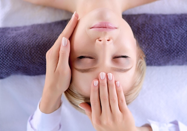 Jeune femme allongée sur une table de massage relaxante avec les yeux fermés femme spa salon