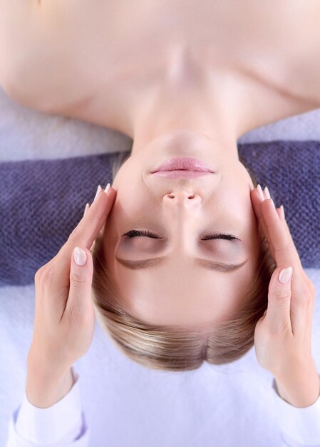 Jeune femme allongée sur une table de massage relaxante avec les yeux fermés femme spa salon