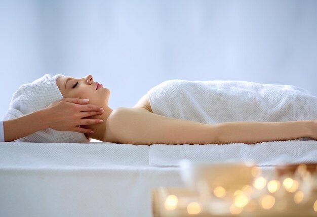 Jeune femme allongée sur une table de massage relaxante avec les yeux fermés femme spa salon