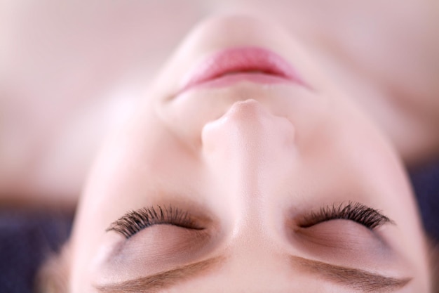 Jeune femme allongée sur une table de massage relaxante avec les yeux fermés femme spa salon