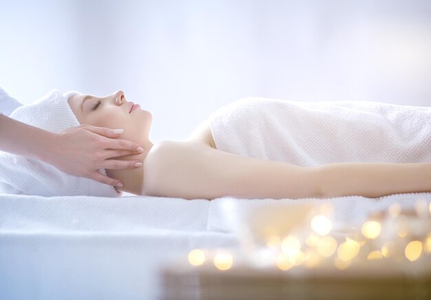 Jeune femme allongée sur une table de massage relaxante avec les yeux fermés femme spa salon