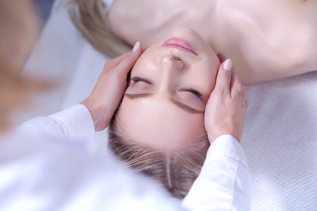 Jeune femme allongée sur une table de massage relaxante avec les yeux fermés femme spa salon