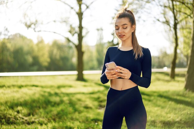 Une jeune femme allume de la musique pour courir sur son smartphone à l'extérieur