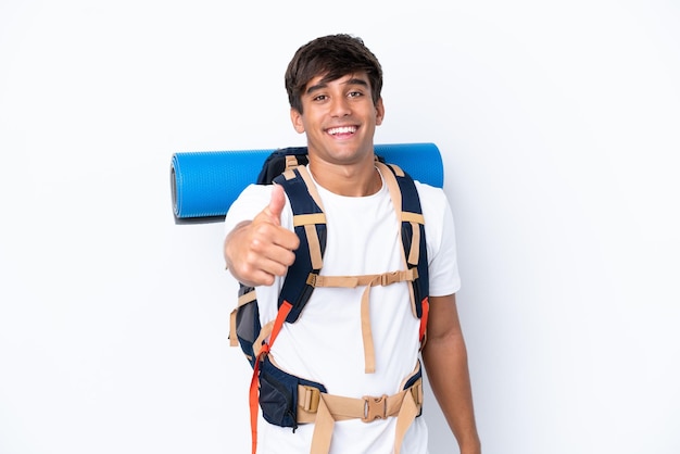 Jeune femme alpiniste avec un gros sac à dos sur fond blanc isolé avec le pouce levé parce que quelque chose de bien s'est produit