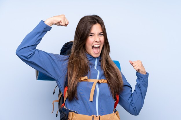 Photo jeune femme alpiniste avec un gros sac à dos sur un mur isolé