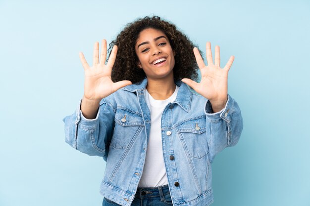 Jeune, femme américaine africaine, sur, mur bleu, compter, dix, à, doigts