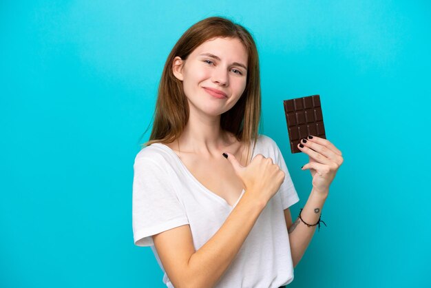 Jeune femme anglaise au chocolat isolée sur fond bleu fière et satisfaite