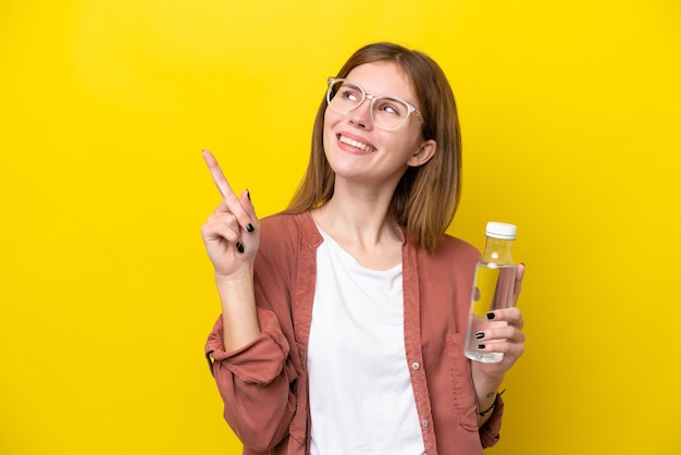 Jeune femme anglaise avec une bouteille d'eau isolée sur fond jaune pointant vers le haut une excellente idée