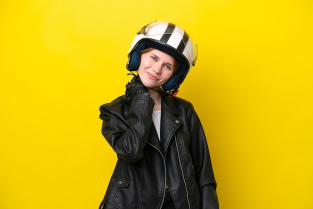 Jeune femme anglaise avec un casque de moto isolé sur fond jaune en riant