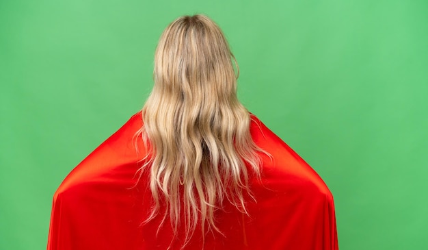 Jeune femme anglaise sur fond isolé en costume de super-héros en position arrière
