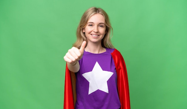 Jeune femme anglaise sur fond isolé en costume de super-héros avec le pouce vers le haut