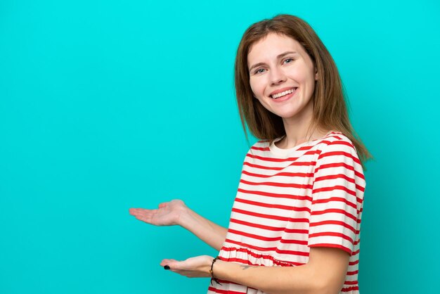 Jeune femme anglaise isolée sur fond bleu étendant les mains sur le côté pour inviter à venir