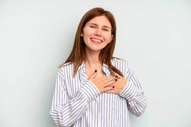 Jeune femme anglaise isolée sur fond bleu a une expression amicale, appuyant la paume sur la poitrine. Notion d'amour.