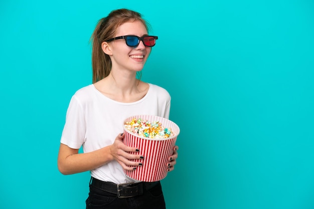 Jeune femme anglaise isolée sur fond bleu avec des lunettes 3d et tenant un grand seau de pop-corn