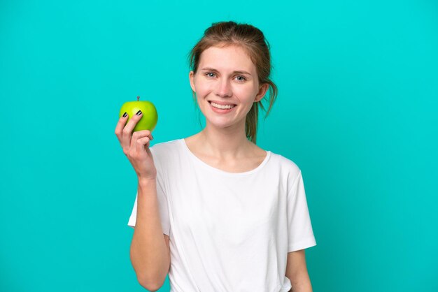 Jeune femme anglaise isolée sur fond bleu avec une pomme