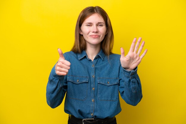 Jeune femme anglaise isolée sur fond jaune comptant six avec les doigts