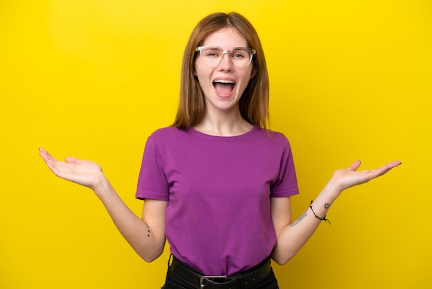 Jeune femme anglaise isolée sur fond jaune avec une expression faciale choquée