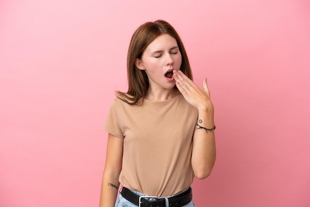 Jeune femme anglaise isolée sur fond rose bâillant et couvrant la bouche grande ouverte avec la main