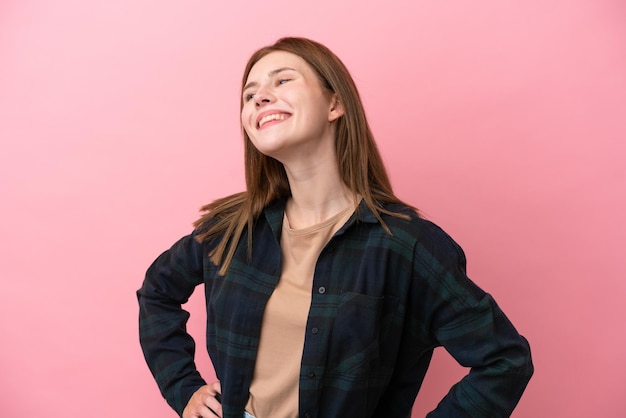 Jeune femme anglaise isolée sur fond rose posant avec les bras à la hanche et souriant