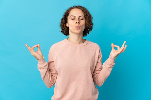 Jeune femme anglaise isolée sur mur bleu en pose zen