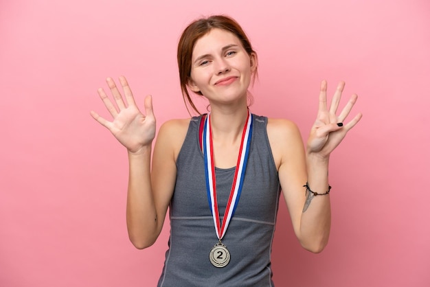 Jeune femme anglaise avec des médailles isolées sur fond rose comptant neuf avec les doigts