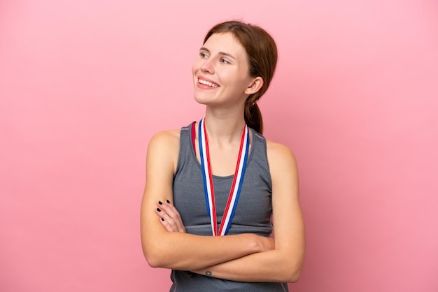 Jeune femme anglaise avec des médailles isolées sur fond rose heureuse et souriante