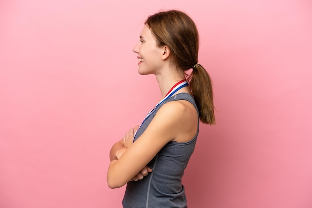 Jeune femme anglaise avec des médailles isolées sur fond rose en position latérale