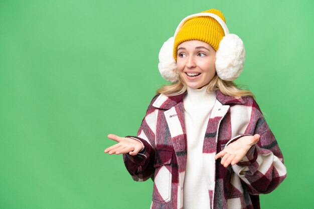 Jeune femme anglaise portant des manchons d'hiver sur fond isolé avec une expression faciale surprise