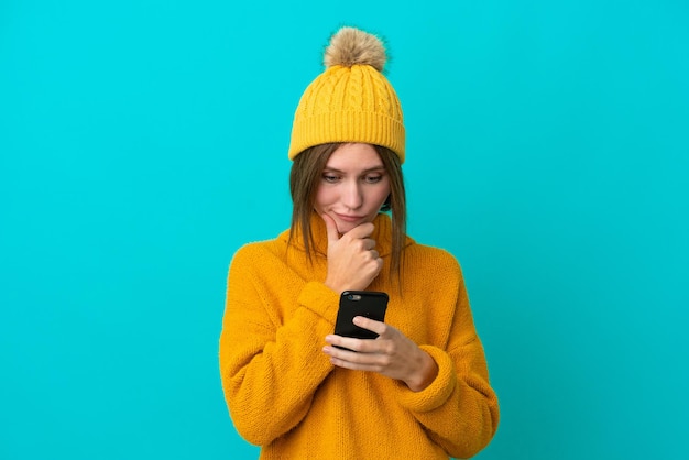 Jeune femme anglaise portant une veste d'hiver isolée sur fond bleu pensant et envoyant un message