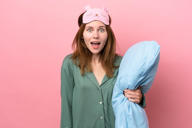 Jeune femme anglaise en pyjama isolée sur fond rose en pyjama et avec une expression faciale surprise et choquée