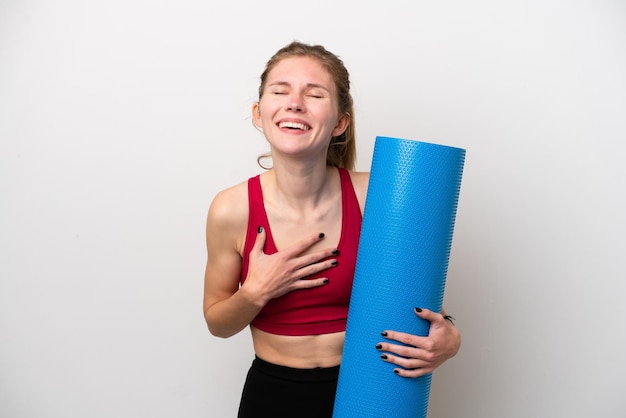 Jeune femme anglaise sportive allant à des cours de yoga tout en tenant un tapis isolé sur fond blanc souriant beaucoup