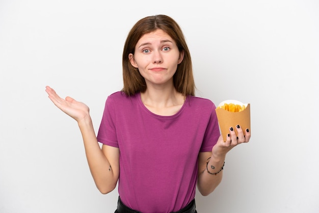 Jeune femme anglaise tenant des frites frites isolées sur fond blanc ayant des doutes tout en levant les mains