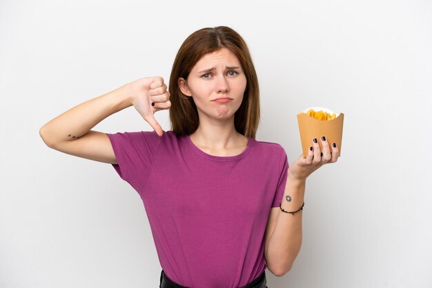 Jeune femme anglaise tenant des frites frites isolées sur fond blanc montrant le pouce vers le bas avec une expression négative