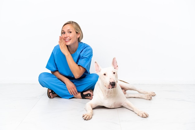 Jeune femme anglaise vétérinaire assise sur le sol avec un chien chuchotant quelque chose