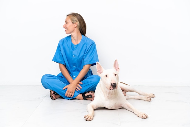 Jeune femme anglaise vétérinaire assise sur le sol avec un chien à côté