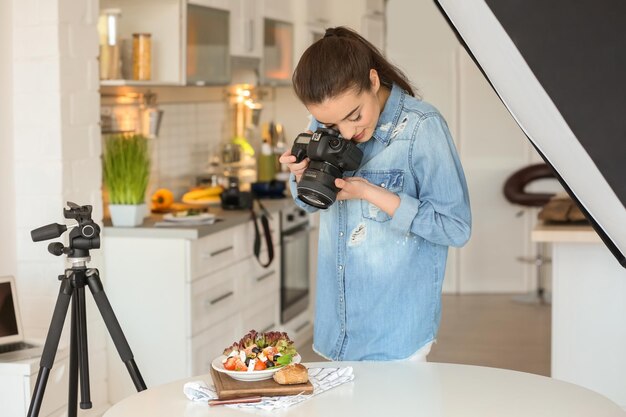 Jeune femme avec appareil photo professionnel prenant des photos de nature morte dans la cuisine