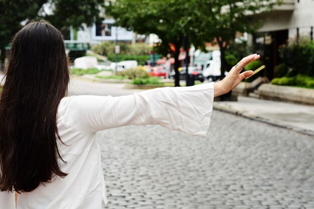 Jeune femme appelant un taxi dans la rue.