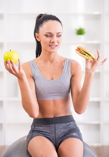 Jeune femme avec apple et hot-dog après l'exercice à la maison.