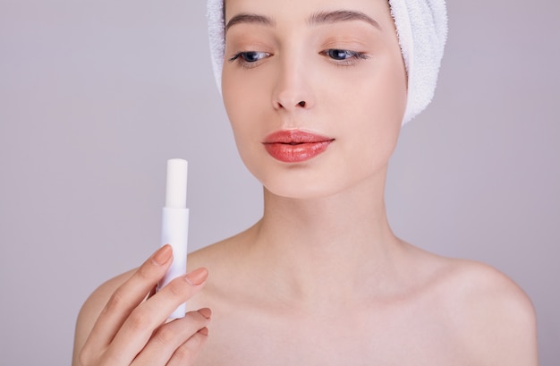 Jeune femme appliquant un baume à lèvres sur le fond.