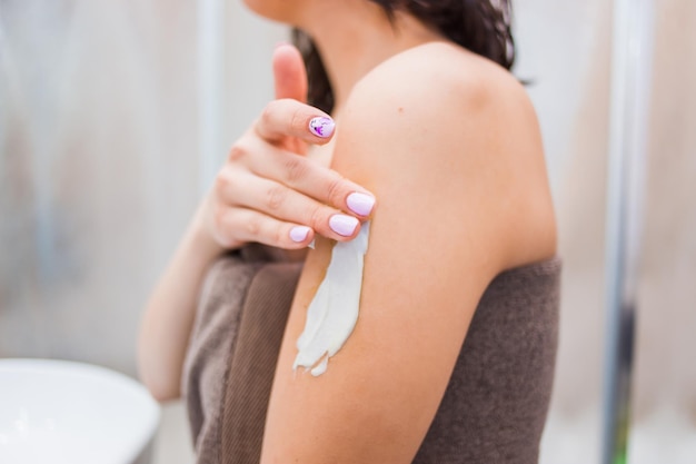 Jeune femme appliquant une crème pour le corps, masque à la maison