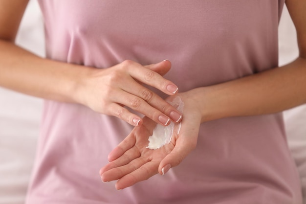 Jeune femme appliquant la crème pour les mains agrandi