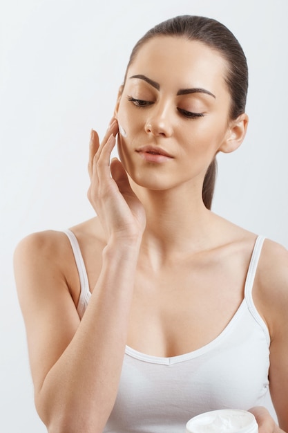 Jeune femme appliquant de la crème sur son visage