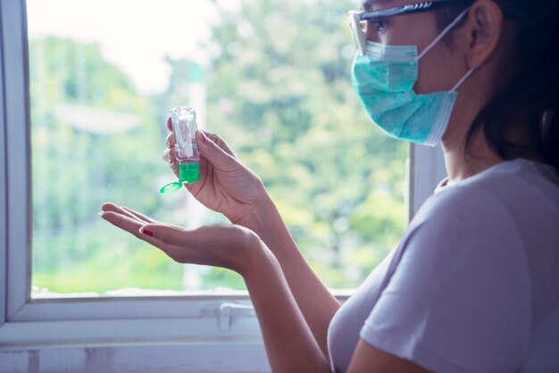 Jeune femme appliquant un désinfectant pour les mains à la maison